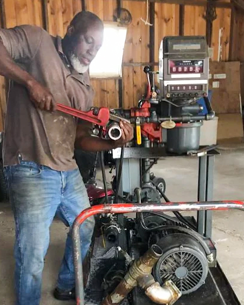 A man inside his shop performing pump repair services for a customer
